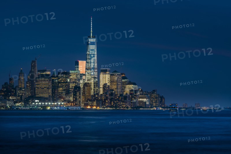 Illuminated cityscape reflecting in river. New York City, New York, USA.