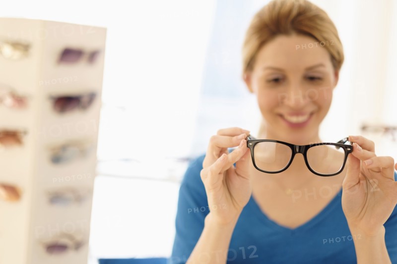 Woman and choosing eyeglasses in store.