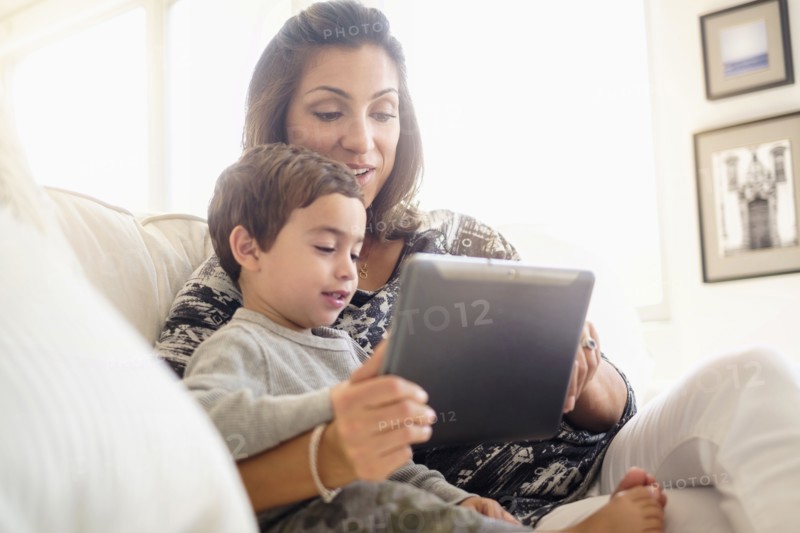 Mother reading with son (2-3) on sofa.