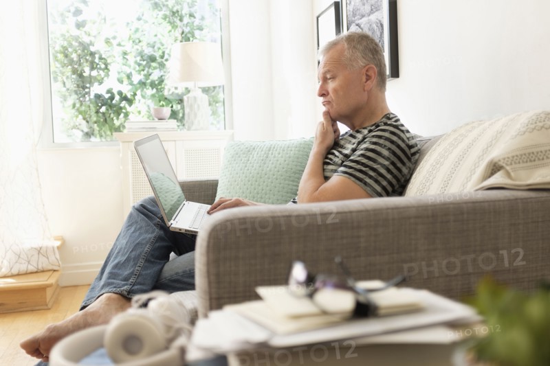 Man sitting on sofa using laptop.