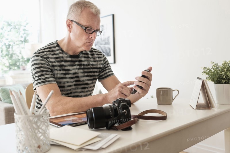 Man in home office using smartphone.