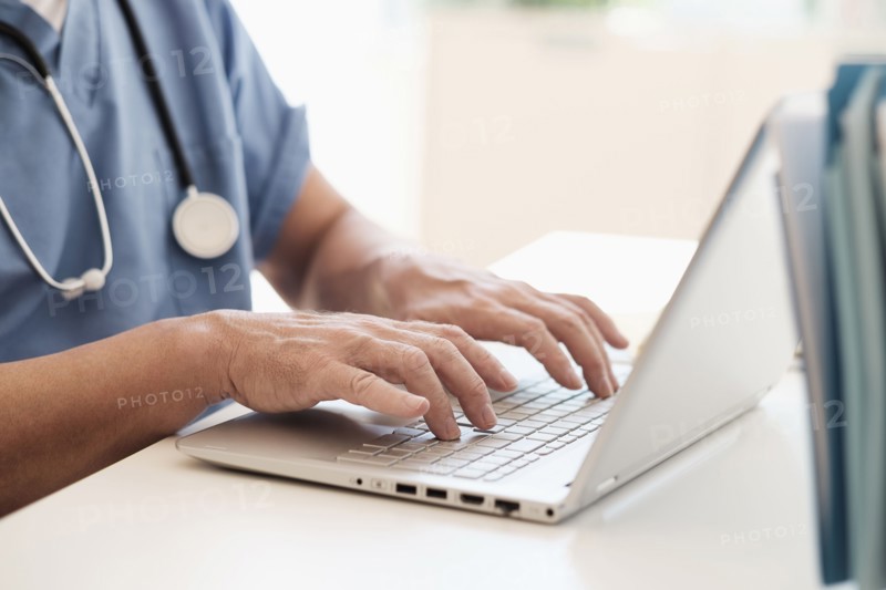 Man in scrubs using laptop.