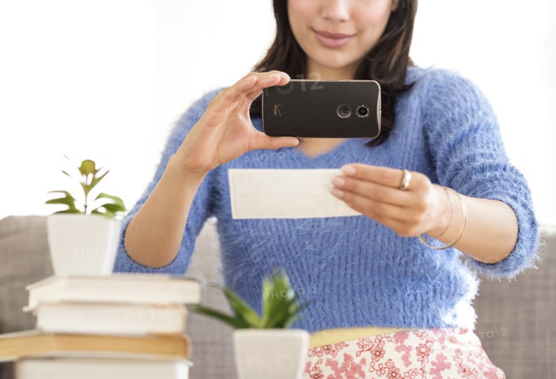 Young woman photographing bank statement.