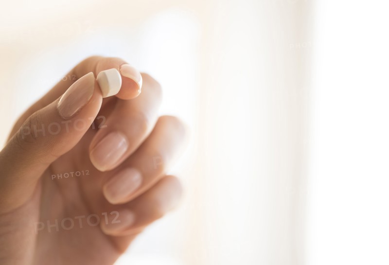 Hand holding vitamin pill.