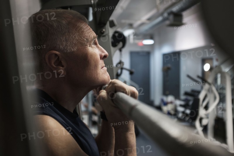 Man in health club doing chin-ups.