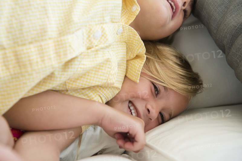 Boy (4-5) and girl (6-7) playing on sofa