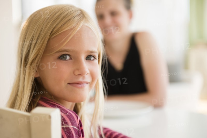 Girl (6-7) looking at camera and woman in background