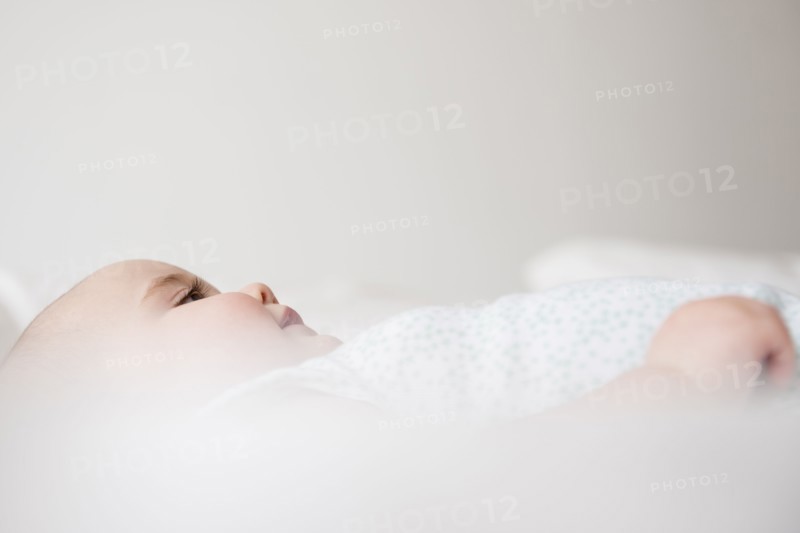 Baby girl (12-17 months) lying down on bed