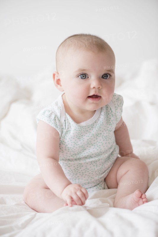 Baby girl (12-17 months) sitting on bed