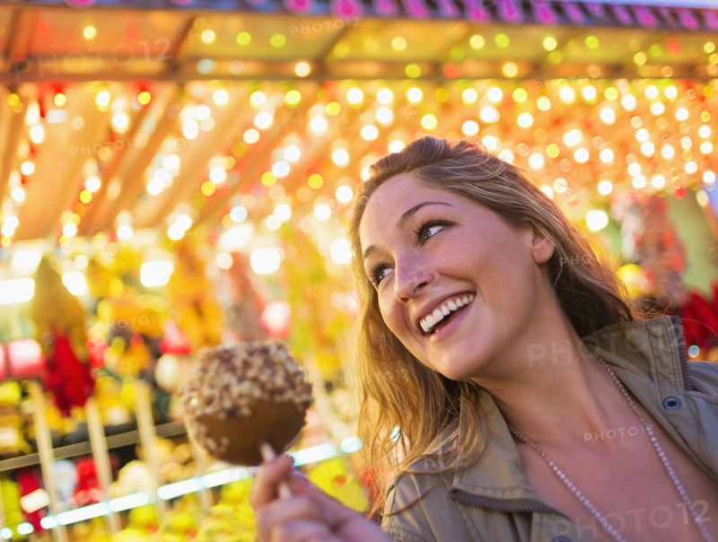 Woman holding caramel apple at funfair
