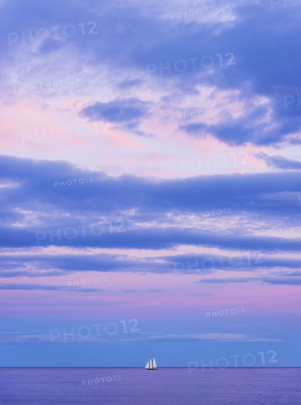 Pastel-colored sunset seascape with sailboat