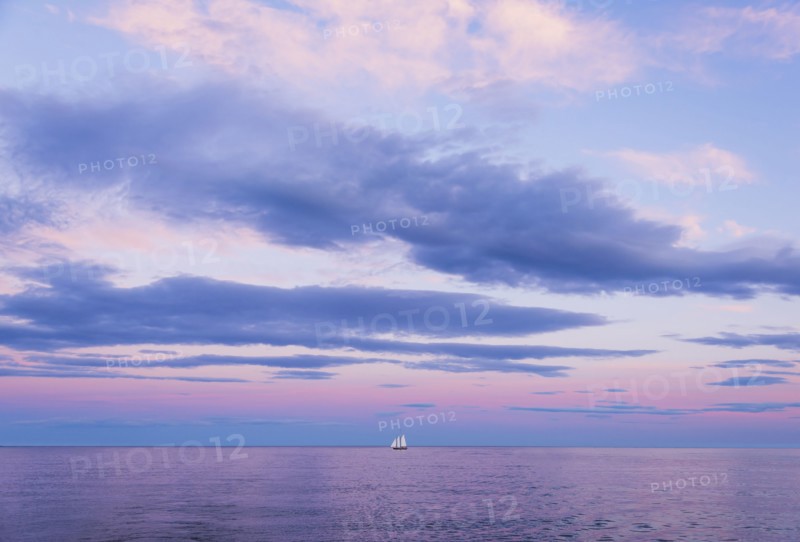 Pastel-colored sunset seascape with sailboat
