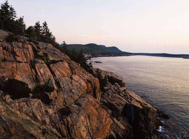 Rocky cliff by sea at sunrise