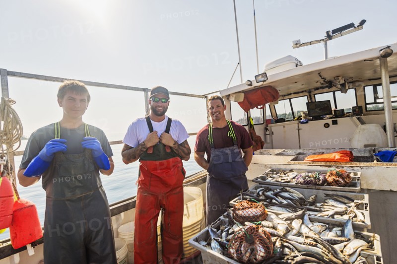 Portrait of three fishermen standing on boat