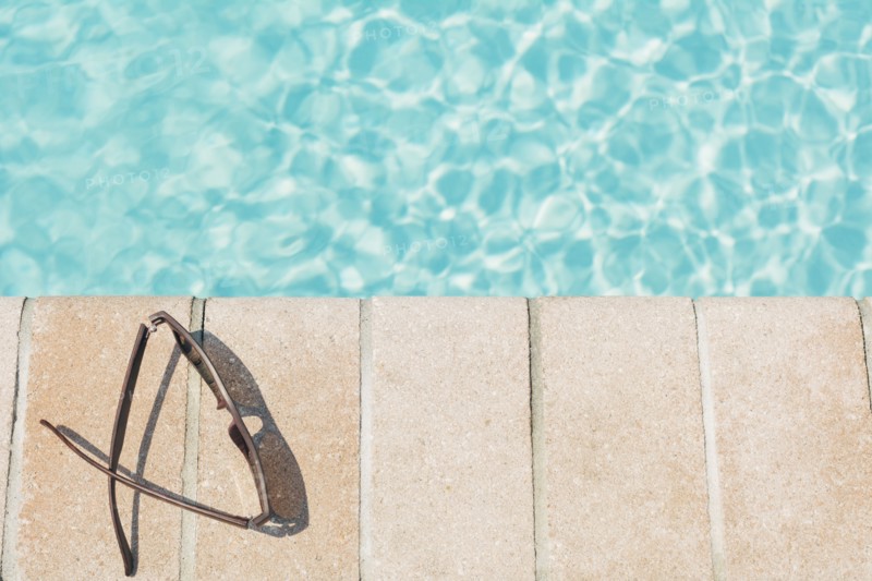 Sunglasses on brick ledge by pool