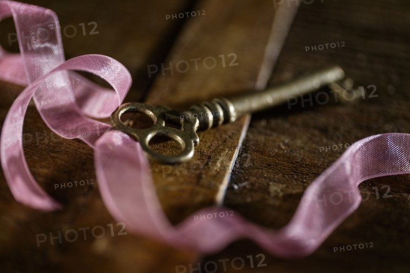Skeleton key and pink ribbon on table.