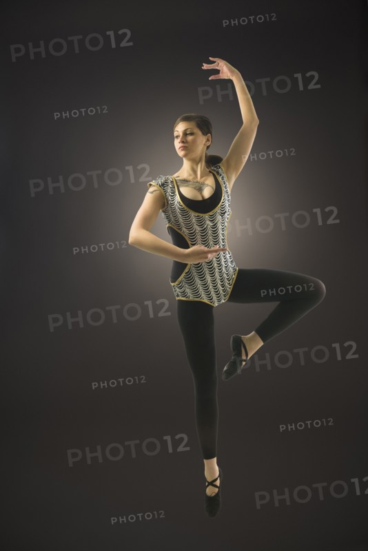 Young woman dancing against black background.