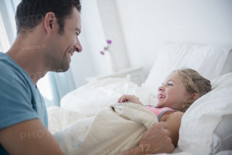 Father tucking daughter (6-7) in bed