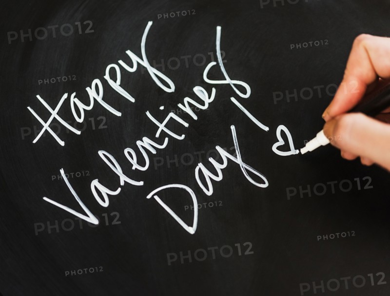 Man's hand writing on black paper