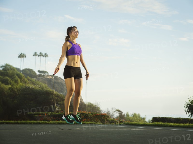 Young woman jumping rope in park
