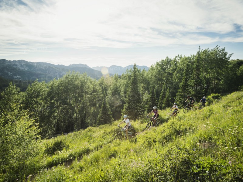 Family with children (10-11, 12-13, 14-15) cycling in mountains