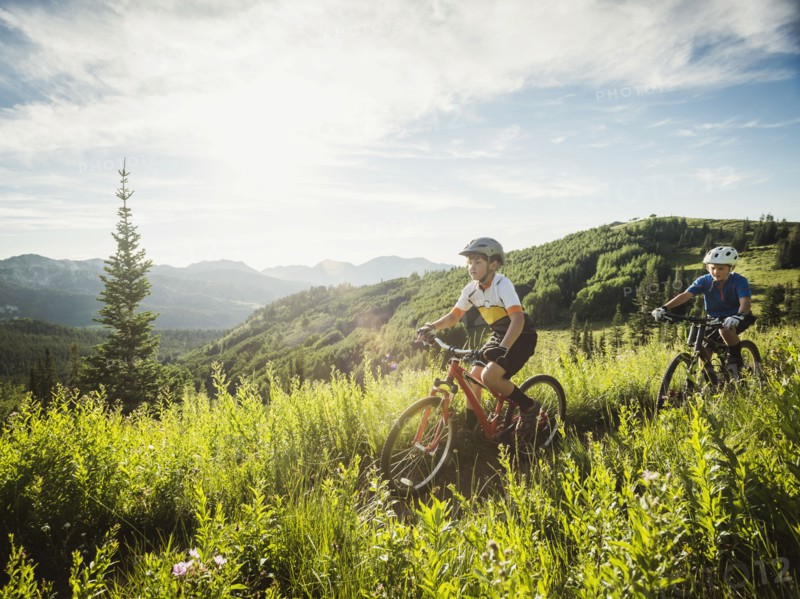 Boys (10-11, 12-13) during bicycle trip in mountain scenery
