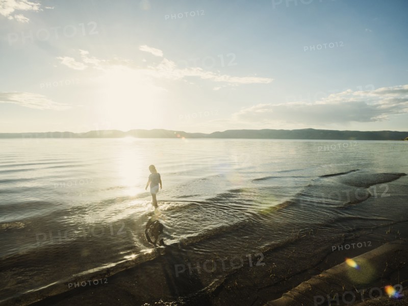 Small girl (4-5) wading in lake on sunny day