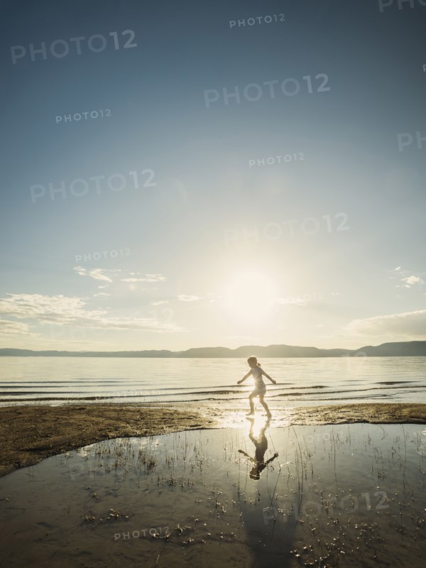 Small girl (4-5) wading in lake on sunny day