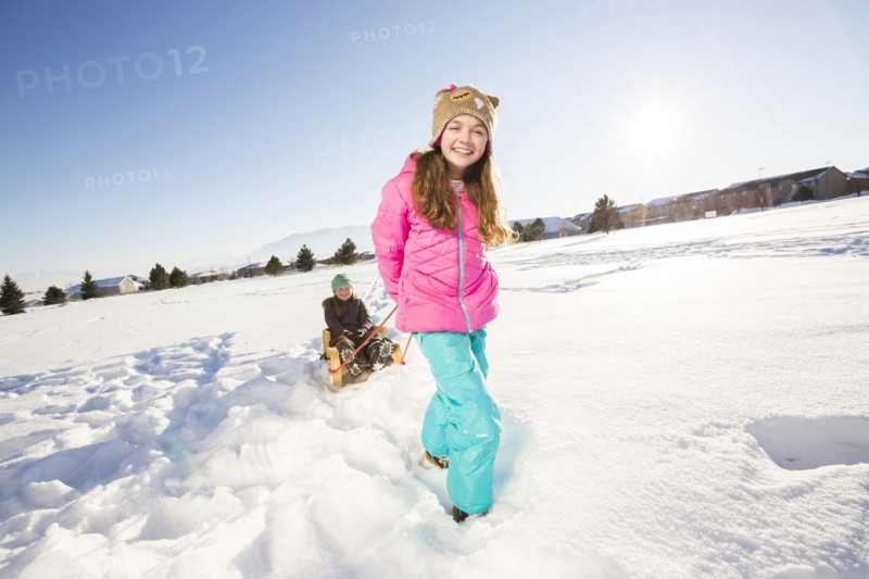Children (8-9, 10-11) playing with sled in snow