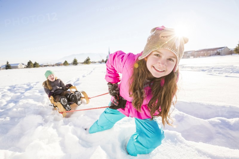 Children (8-9, 10-11) playing with sled in snow