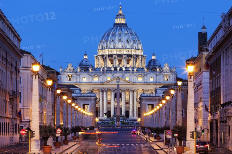 Illuminated St. Peter's Basilica with asphalt road in foreground at dusk