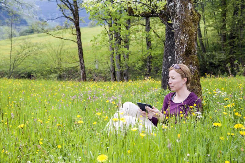 Woman using e-reader in meadow