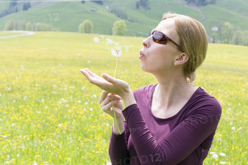 Woman blowing on dandelion