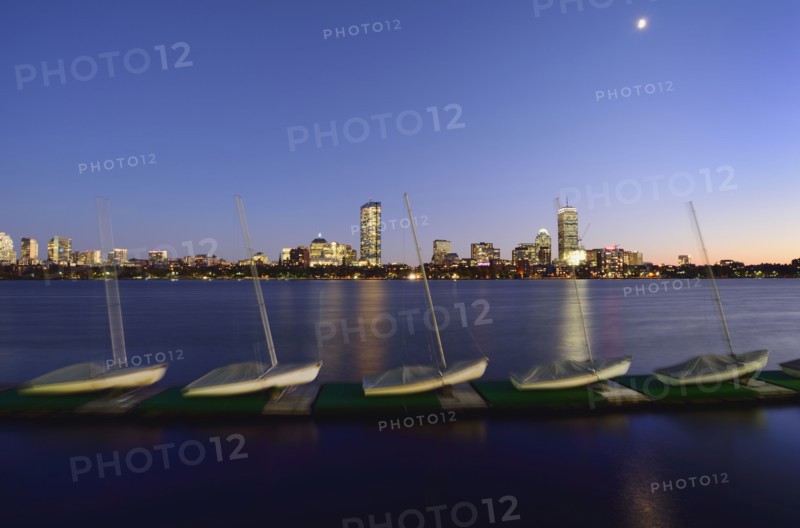Sail boats in row on pier, cityscape in background