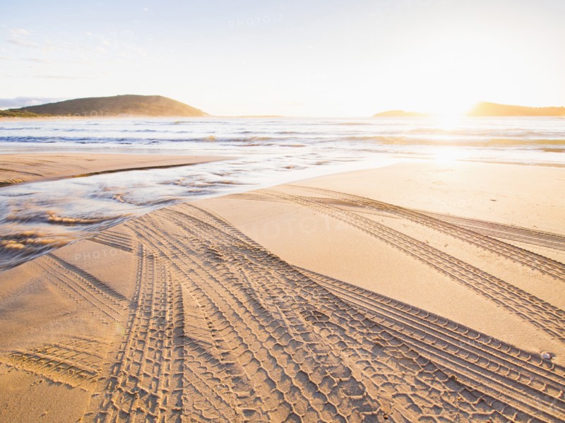 Tire tracks on beach at sunset