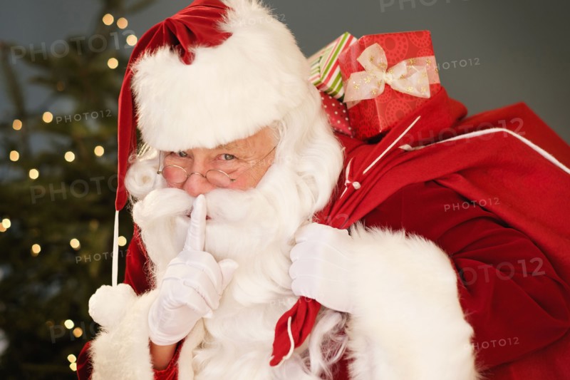 Portrait of Santa Claus with finger on lips, carrying sack over shoulder.