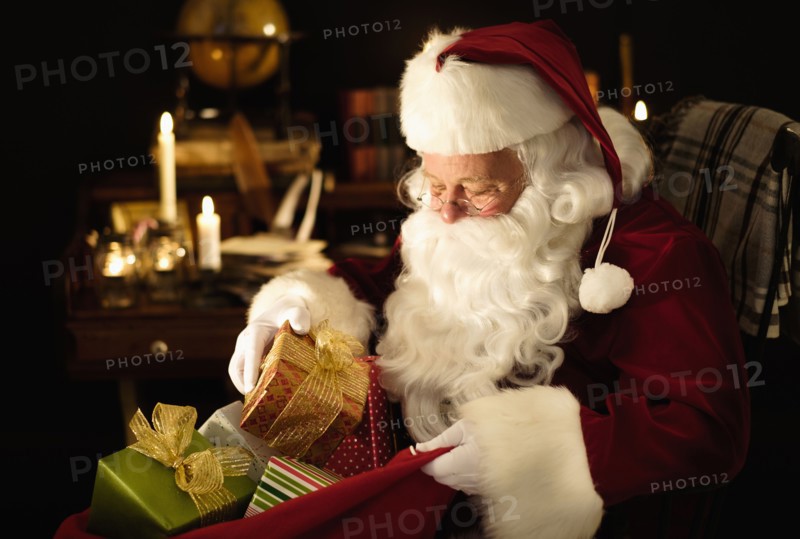 Santa Claus packing Christmas presents to sack.