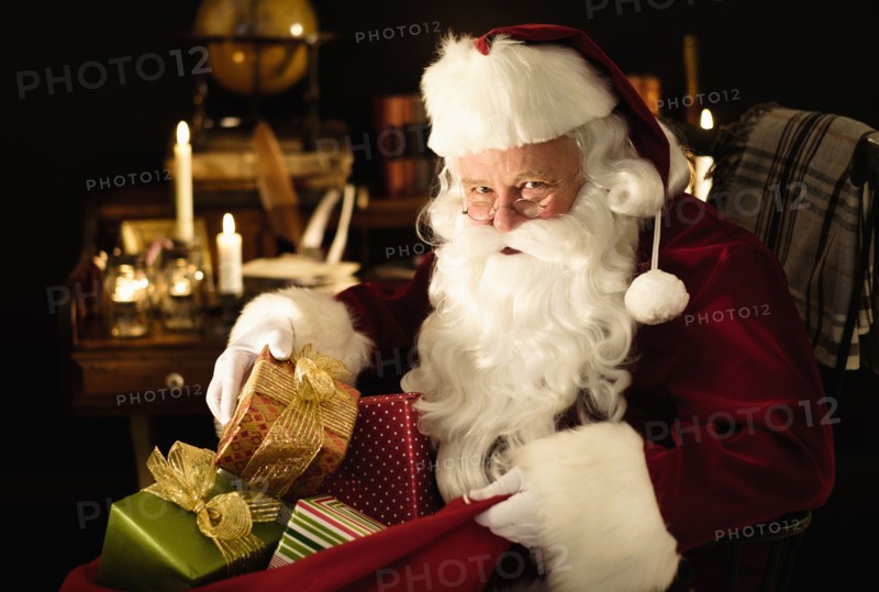 Santa Claus packing Christmas presents to sack.