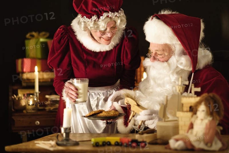 Mrs. Claus bringing homemade cookies to Santa Claus.