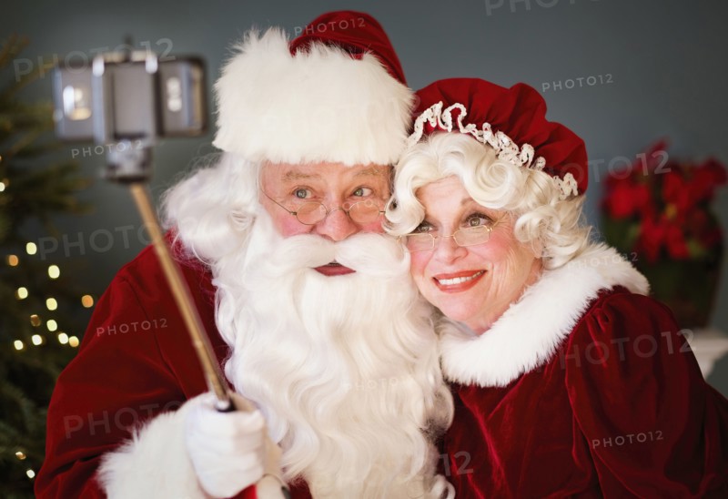 Santa and Mrs. Santa taking selfie with monopod.
