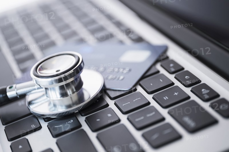 Stethoscope and credit card lying on laptop.