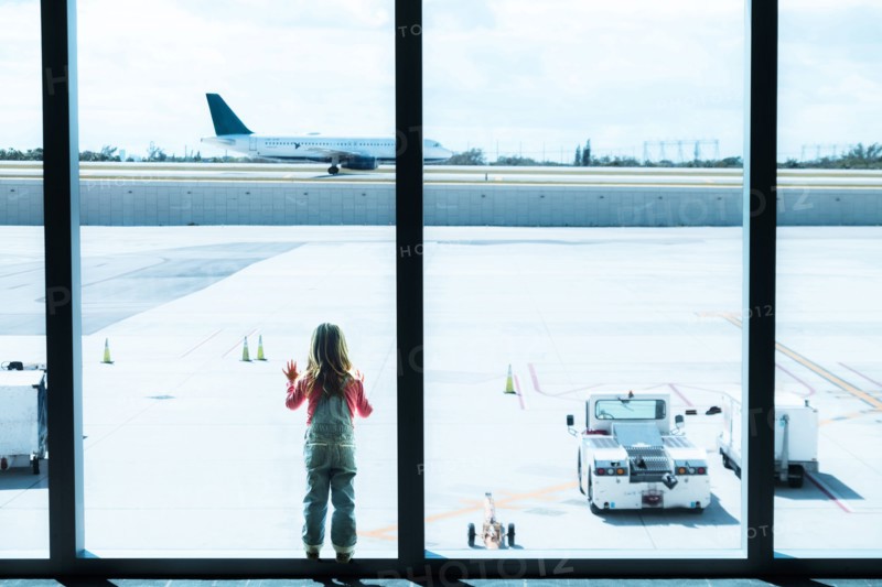 Girl (2-3) looking through window at airport.
