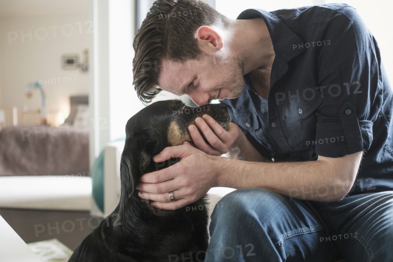 Man playing with dog in living room.