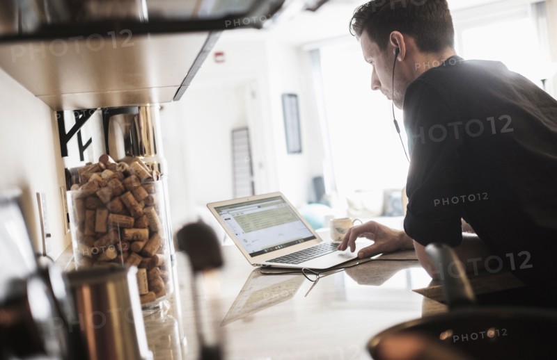 Man working on laptop computer in kitchen.