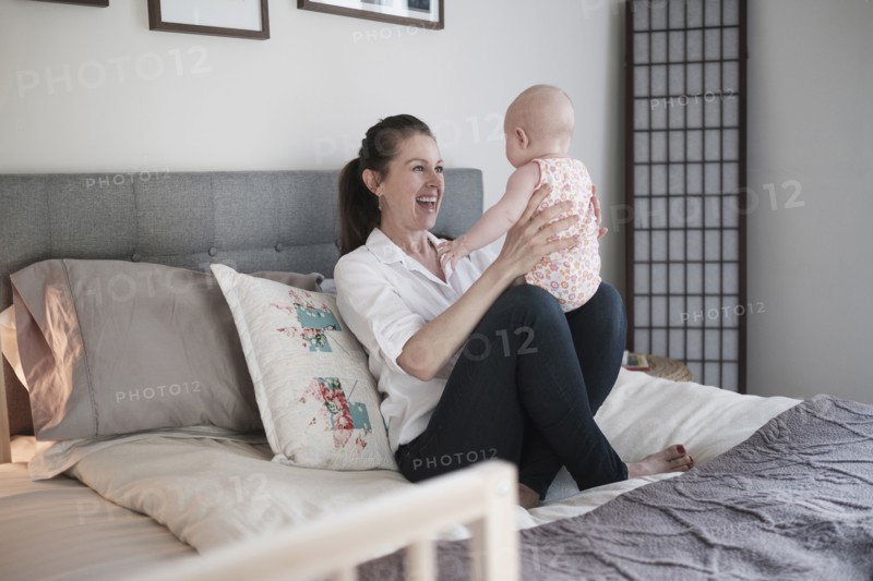 Mother playing with baby daughter (2-5 months) in bedroom.