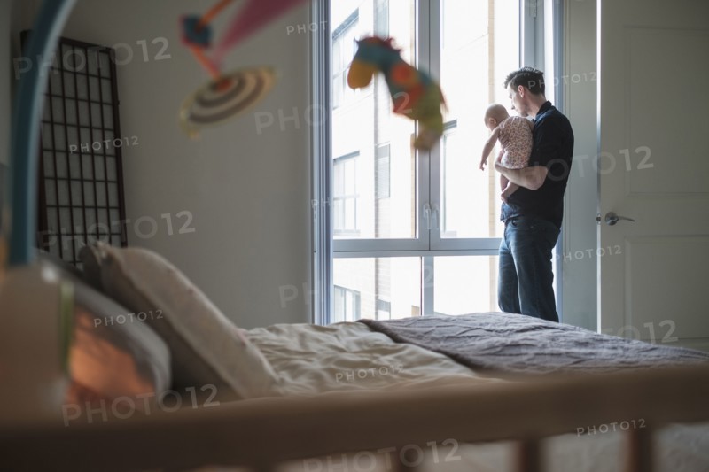 Father looking through window with daughter (2-5 months).
