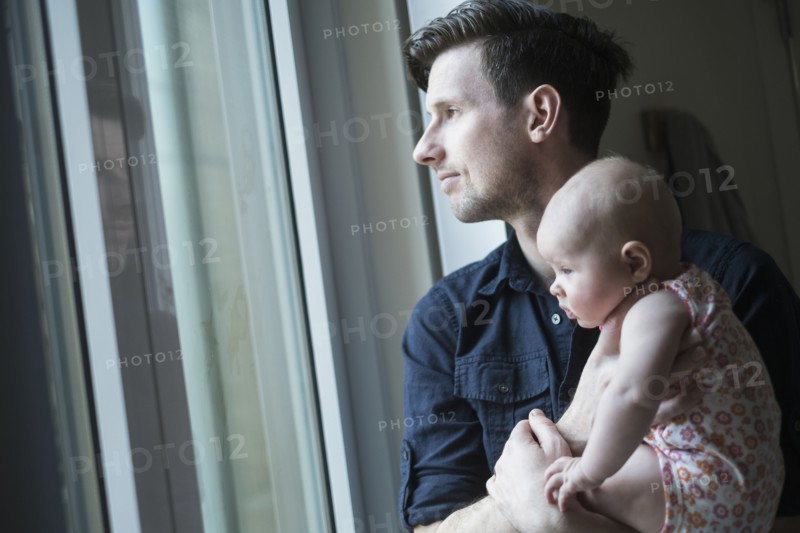 Father looking through window with daughter (2-5 months).