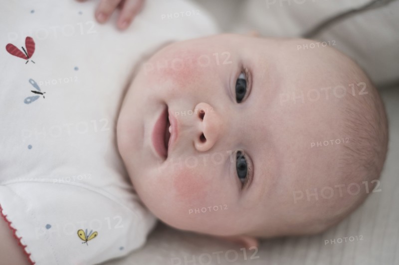 Cute baby girl (2-5 months) lying on bed.