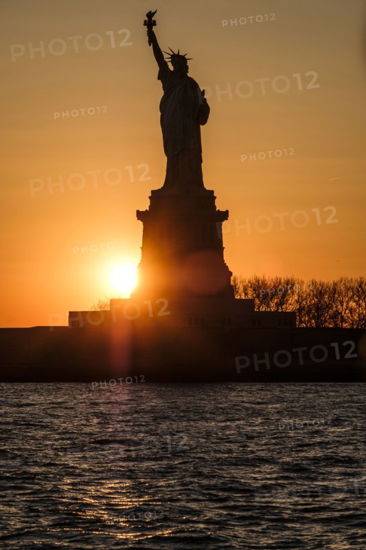 Silhouette of Statue of Liberty at sunset. USA, New York, New York City.