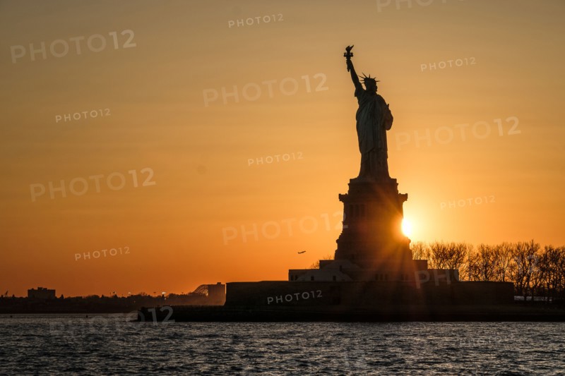 Silhouette of Statue of Liberty at sunset. USA, New York, New York City.